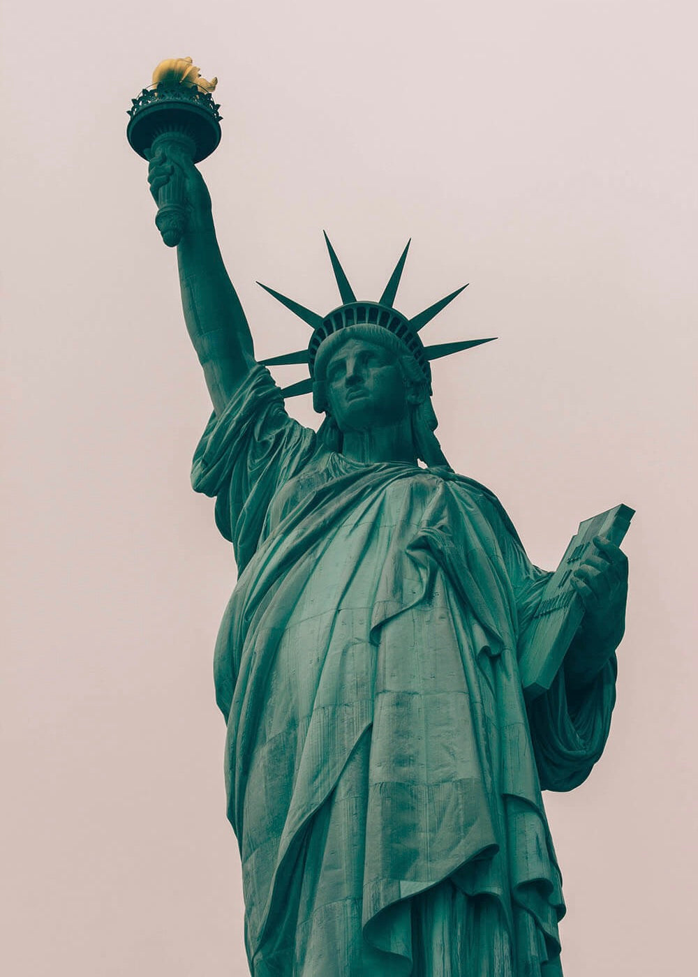 Frihedsgudinden-plakaten fra Posters viser den ikoniske Frihedsgudinde med en løftet fakkel og en tablet i hånden mod en overskyet himmel, hvilket gør den til et slående motiv i ethvert rum.