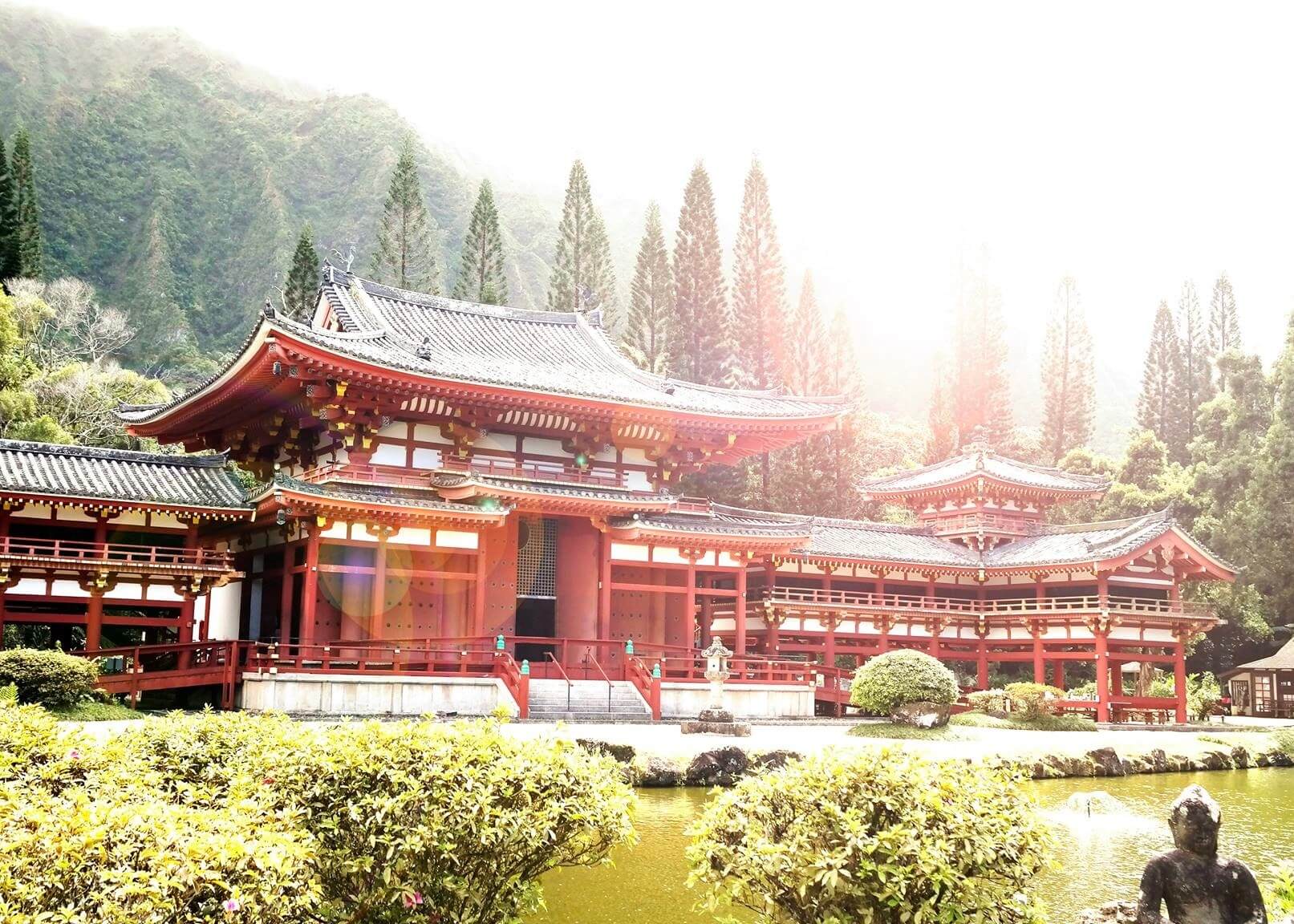 Japansk Palads-plakaten fra Posters viser traditionel rød og hvid japansk arkitektur ved en dam, omgivet af grønne træer og bjerge i sollys, hvilket skaber en meditativ stemning og autentisk japansk plakatstil.