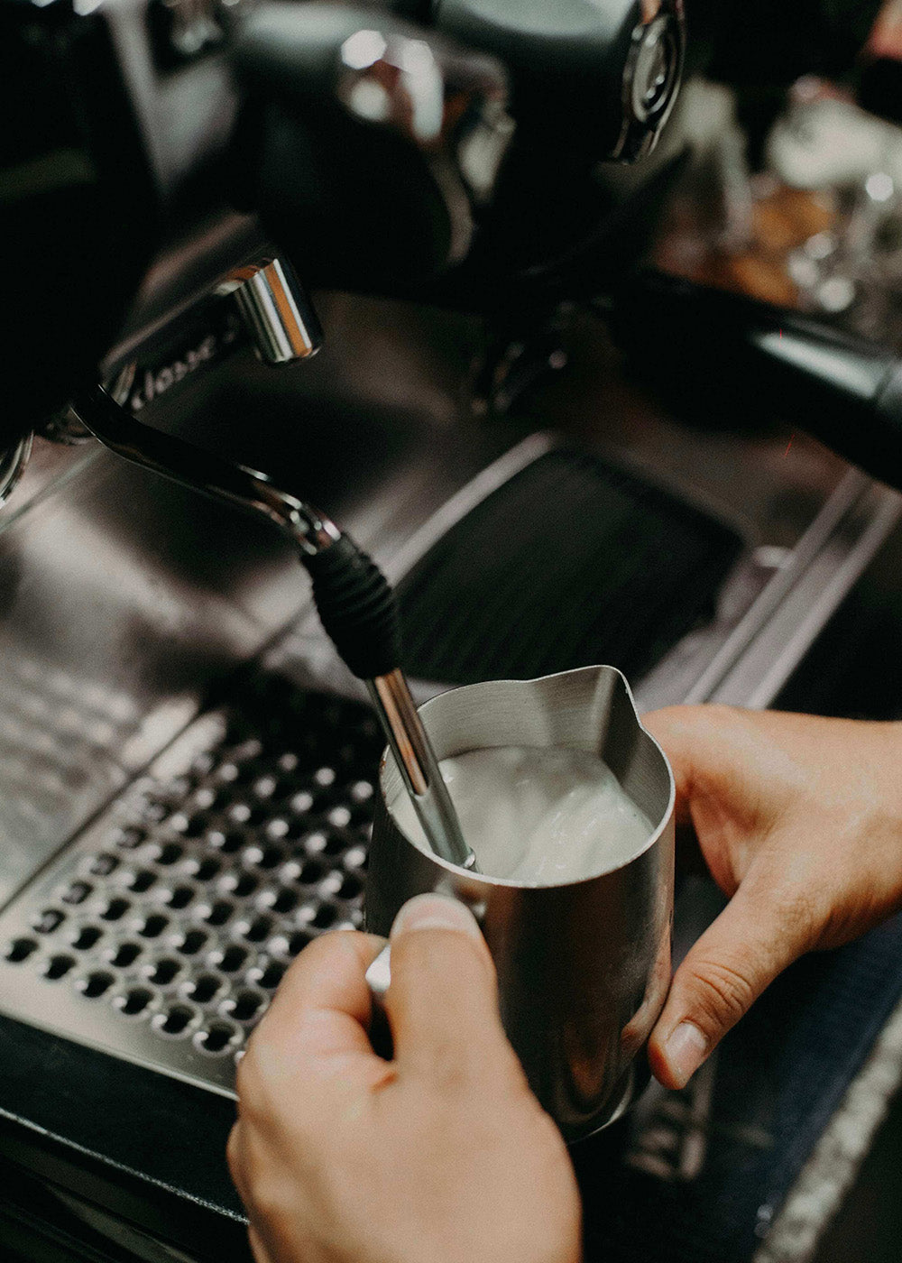 Plakaten "Mælken steames" fra Posters viser mælk, der dampes i en metalkande med en espressomaskines dampstav, hvilket skaber cremet skum til kaffen - et ideelt hyggeprint til kaffeelskere.