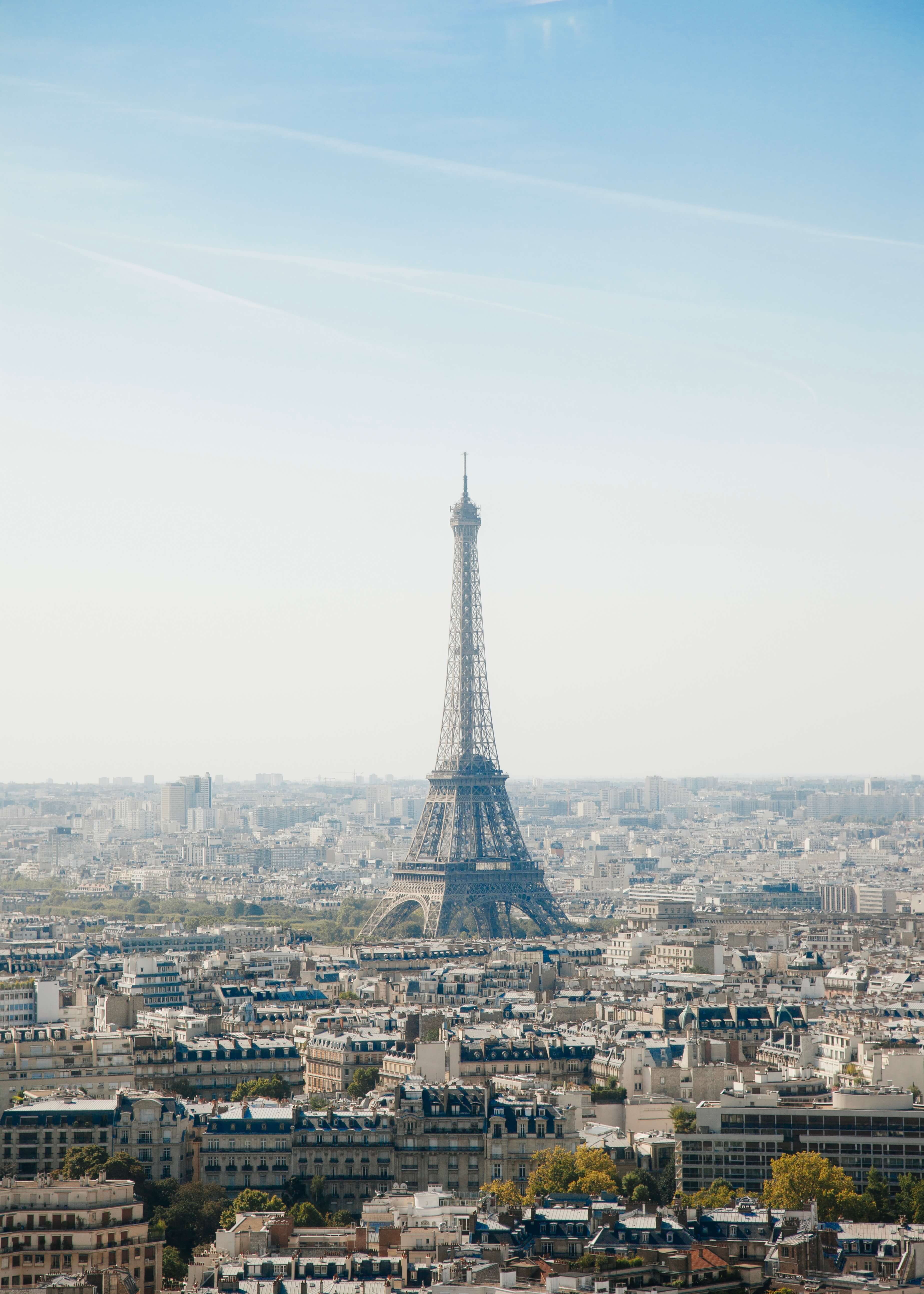 Oversigt over Paris" fra Posters indfanger Eiffeltårnet over Paris' hustage og historiske bygninger mod en klar blå himmel og fremkalder charmen ved et vintageplakat.